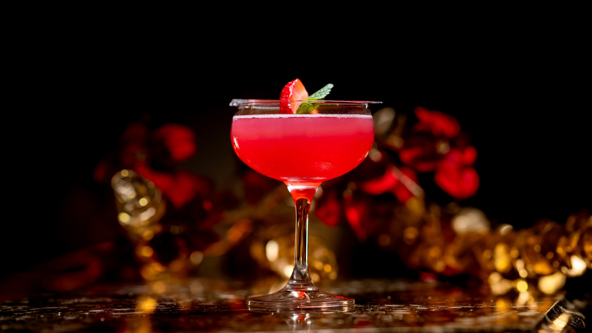 Golden Moonfire Cocktail: Pomegranate martini served with a strawberry-mint garnish