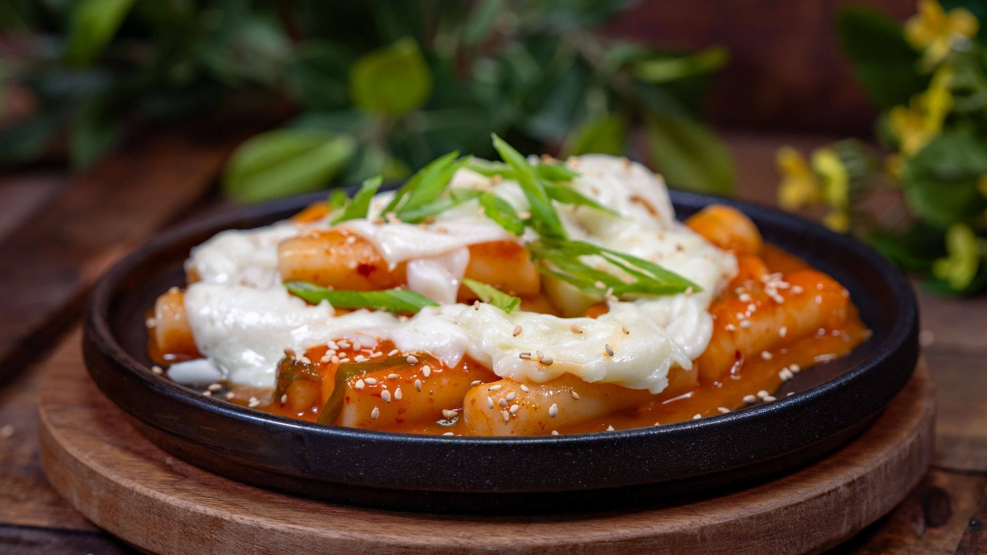 Tteokbokki: Rice cakes with gochujang sauce topped with cheese, sesame seeds, and green onions